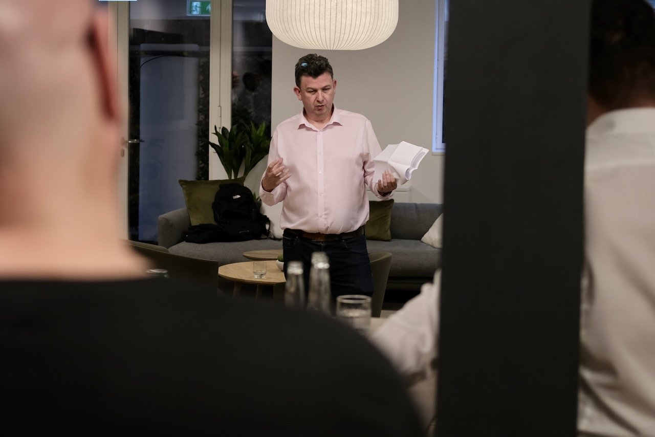 Professor Andy Pardoe giving a presentation in an office environment to a number of cyber security professionals